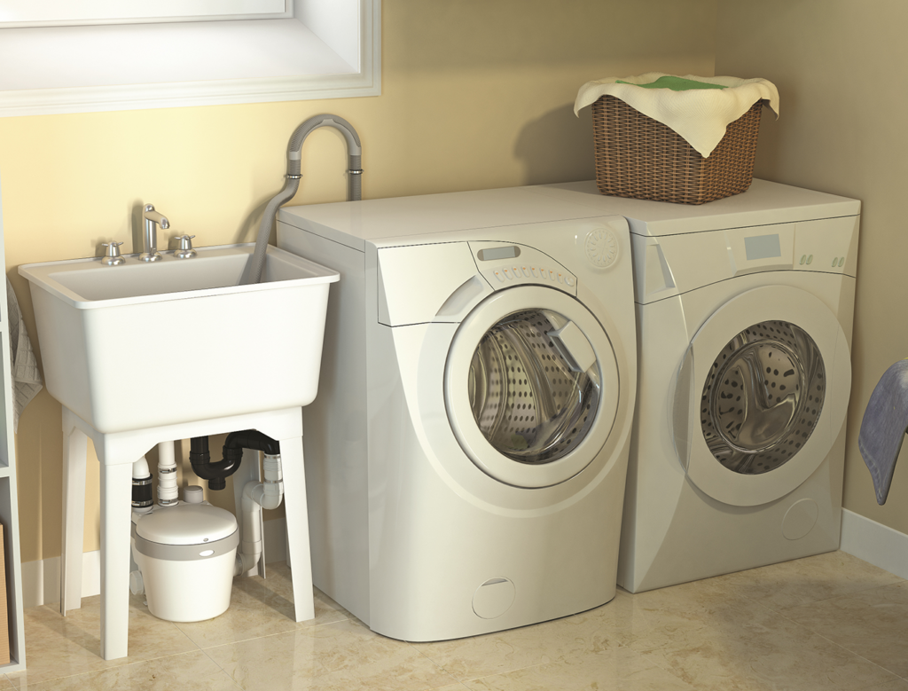 "Image of an above-grade sump kit installed beneath a laundry sink, next to a washer and dryer in a laundry room."